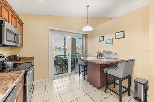 22 San Carlos Dr, Palm Coast, FL 32137 - kitchen featuring stainless steel appliances, a breakfast bar area, brown cabinets, pendant lighting, and light tile patterned floors