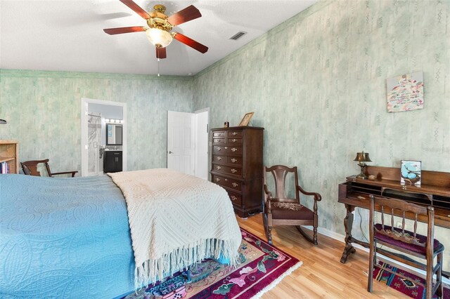 22 San Carlos Dr, Palm Coast, FL 32137 - bedroom featuring wood finished floors, wallpapered walls, a ceiling fan, ensuite bath, and baseboards