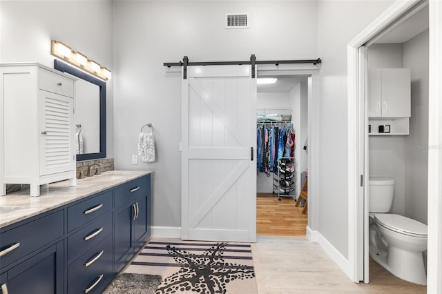 22 San Carlos Dr, Palm Coast, FL 32137 - full bathroom featuring wood finished floors, vanity, toilet, baseboards, and a spacious closet