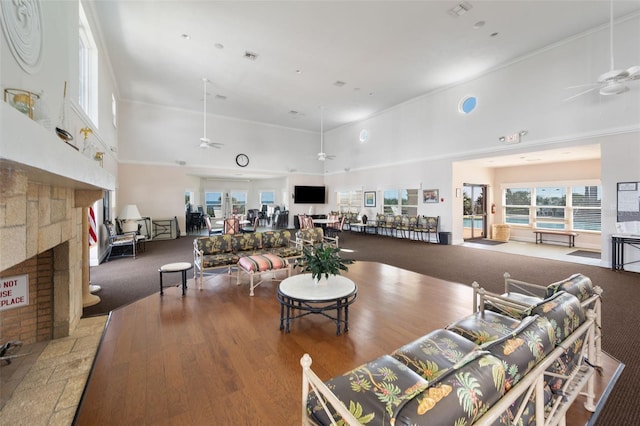 22 San Carlos Dr, Palm Coast, FL 32137 - living area featuring a ceiling fan, a stone fireplace, a high ceiling, carpet floors, and wood finished floors