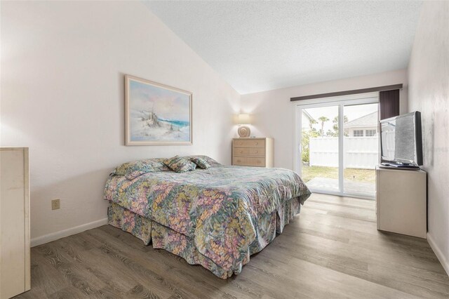 50 Nantucket Dr, Palm Coast, FL 32137 - bedroom featuring access to outside, vaulted ceiling, wood finished floors, baseboards, and a textured ceiling
