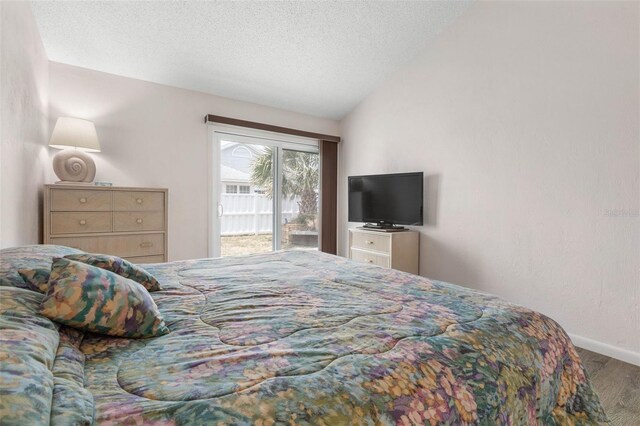 50 Nantucket Dr, Palm Coast, FL 32137 - bedroom with access to exterior, wood finished floors, lofted ceiling, baseboards, and a textured ceiling