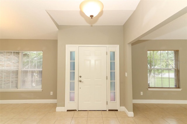 entryway with light tile patterned floors, baseboards, and plenty of natural light