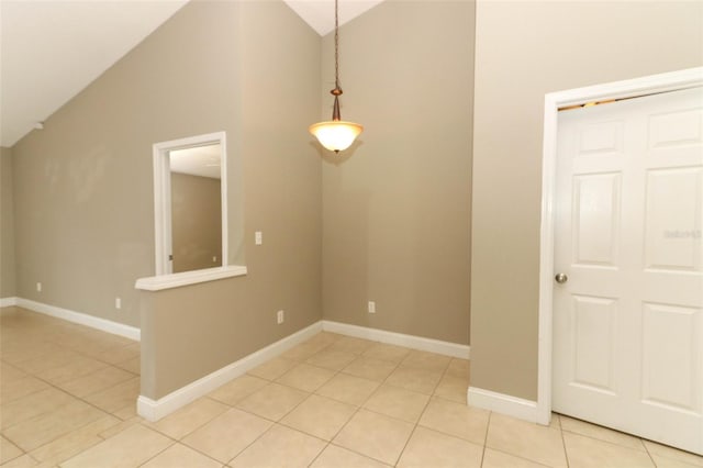empty room featuring baseboards, high vaulted ceiling, and light tile patterned floors