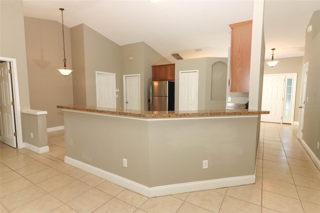 kitchen with a peninsula, light tile patterned floors, freestanding refrigerator, baseboards, and vaulted ceiling