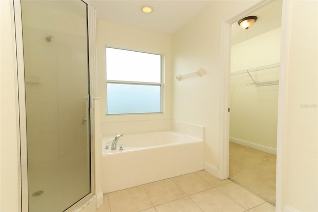 full bathroom with tile patterned flooring, a spacious closet, a shower stall, baseboards, and a bath
