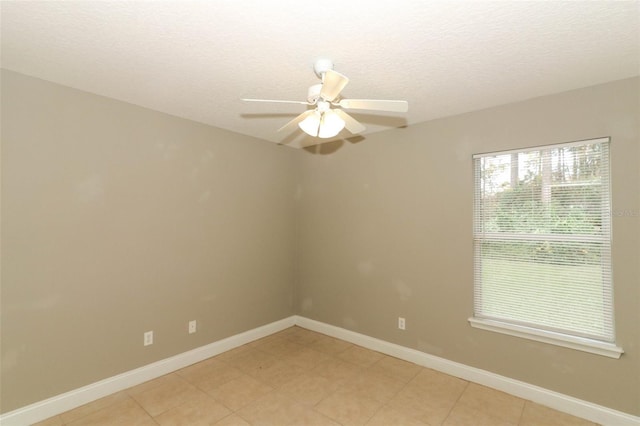 empty room with light tile patterned flooring, a textured ceiling, baseboards, and a ceiling fan