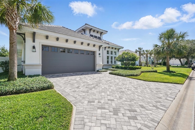 17 Kingfisher Ln, Palm Coast, FL 32137 - view of front facade featuring a garage, decorative driveway, stucco siding, a front lawn, and a tile roof