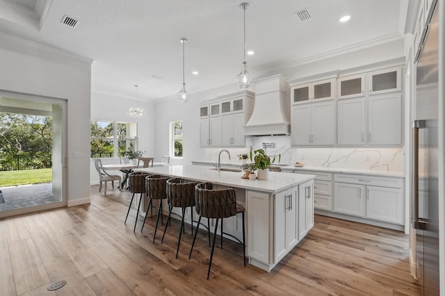 17 Kingfisher Ln, Palm Coast, FL 32137 - kitchen featuring ornamental molding, custom exhaust hood, a sink, healthy amount of natural light, and an island with sink