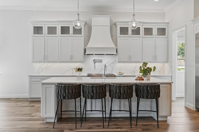 17 Kingfisher Ln, Palm Coast, FL 32137 - kitchen featuring custom exhaust hood, a center island with sink, a kitchen bar, backsplash, and ornamental molding
