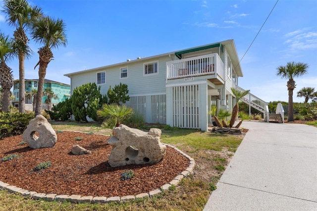 6973 N Oceanshore Blvd, Palm Coast, FL 32137 - view of front of house featuring stairway, driveway, and a balcony
