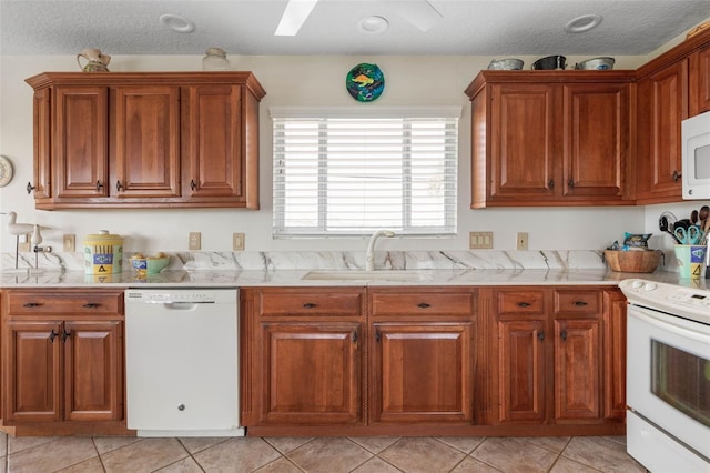 6973 N Oceanshore Blvd, Palm Coast, FL 32137 - kitchen with white appliances, light countertops, brown cabinets, light tile patterned floors, and a sink
