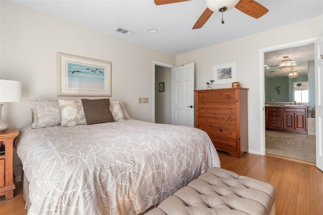 6973 N Oceanshore Blvd, Palm Coast, FL 32137 - bedroom with light wood-type flooring, a sink, ensuite bathroom, and a ceiling fan