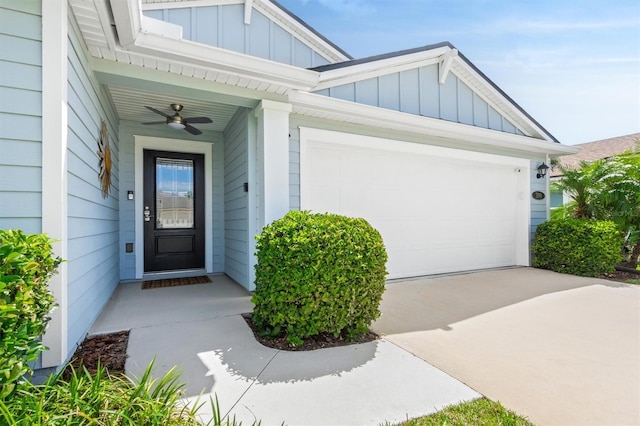 view of exterior entry featuring board and batten siding, ceiling fan, driveway, and a garage