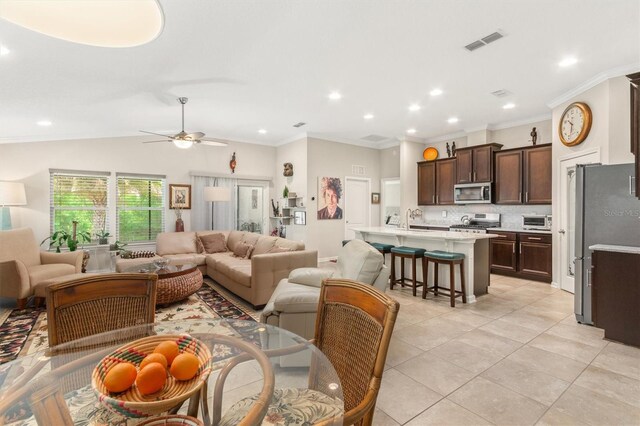 living area featuring light tile patterned floors, a ceiling fan, ornamental molding, and recessed lighting