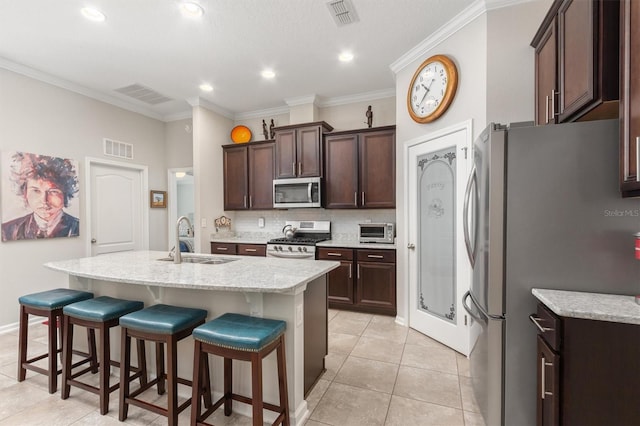 kitchen featuring stainless steel appliances, a sink, a kitchen breakfast bar, a kitchen island with sink, and dark brown cabinets