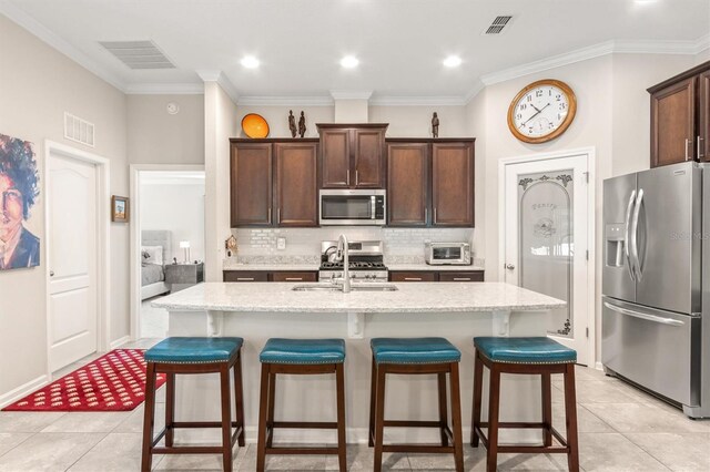 kitchen featuring stainless steel appliances, a sink, backsplash, ornamental molding, and a breakfast bar