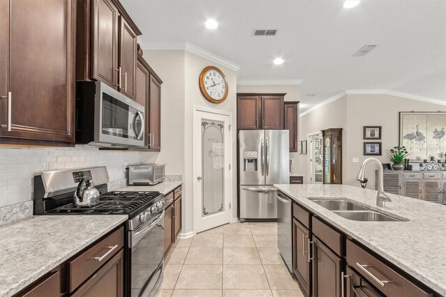 kitchen with stainless steel appliances, a sink, backsplash, dark brown cabinetry, and light tile patterned floors