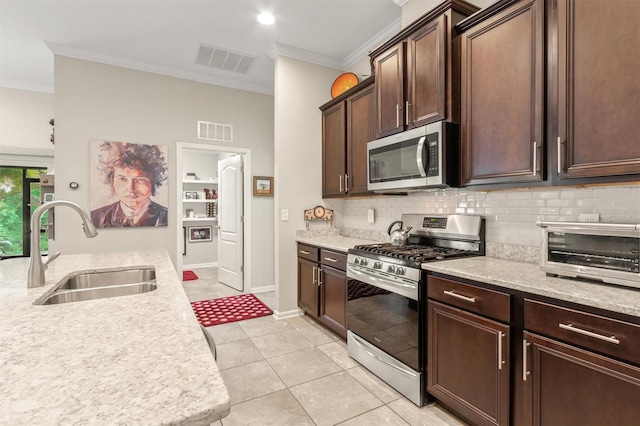 kitchen with appliances with stainless steel finishes, a sink, ornamental molding, tasteful backsplash, and dark brown cabinets