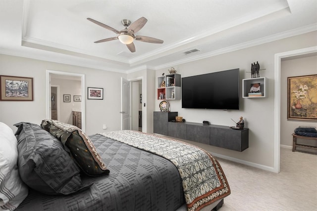 bedroom with a raised ceiling, light colored carpet, ornamental molding, baseboards, and ensuite bath