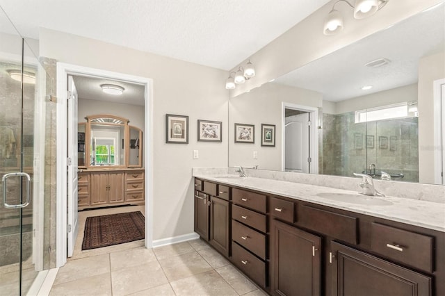 full bath featuring a shower stall, double vanity, tile patterned flooring, and baseboards