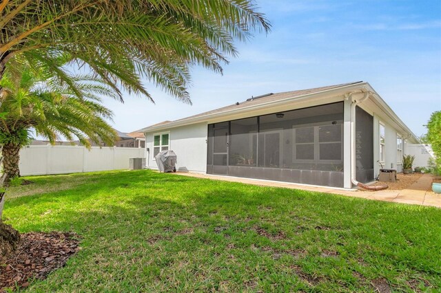 rear view of house featuring a sunroom, stucco siding, and central AC unit
