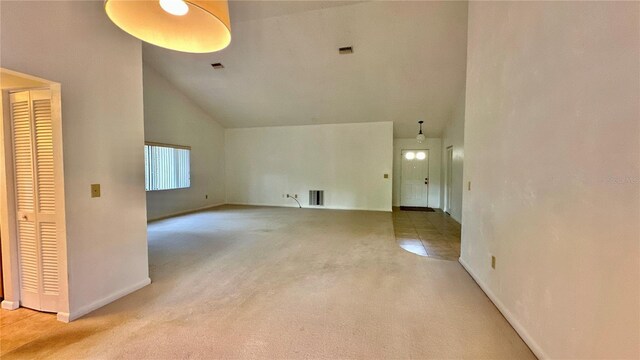 unfurnished living room with high vaulted ceiling, carpet floors, and baseboards