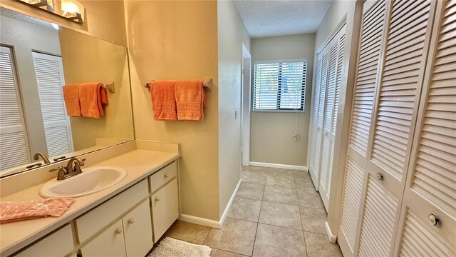 full bathroom featuring a closet, vanity, tile patterned floors, baseboards, and a textured ceiling