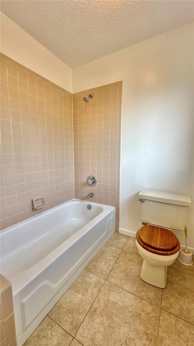 full bath featuring tile patterned flooring, toilet, a textured ceiling, and tub / shower combination