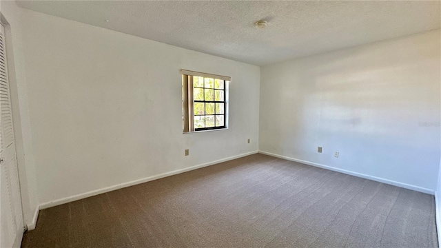 carpeted empty room featuring baseboards, a smoke detector, and a textured ceiling