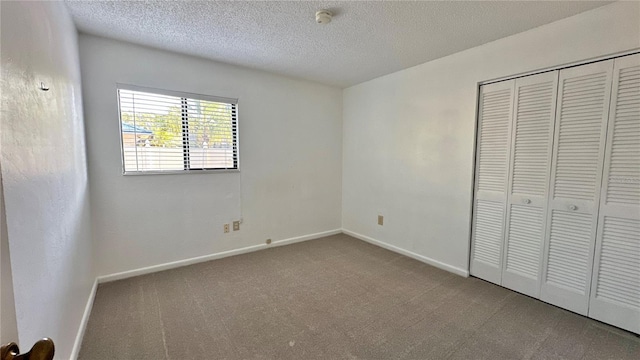 unfurnished bedroom featuring carpet, a closet, baseboards, and a textured ceiling
