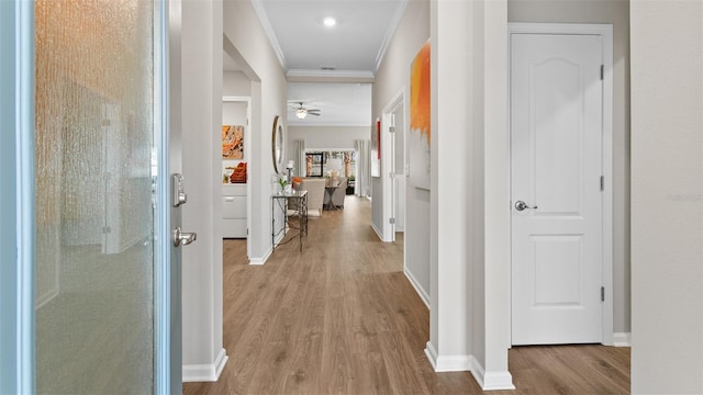 corridor with wood finished floors, baseboards, and ornamental molding