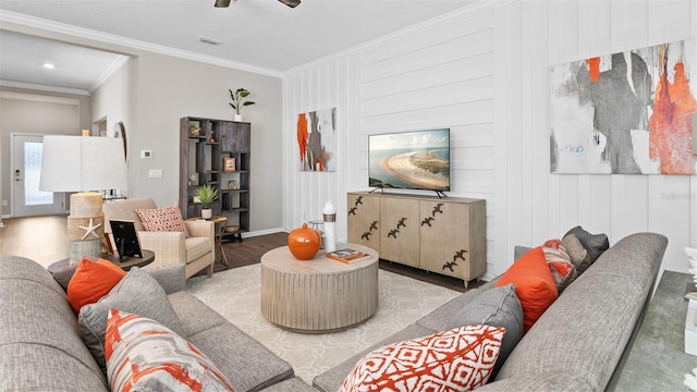 living room with wood finished floors, visible vents, crown molding, a ceiling fan, and baseboards