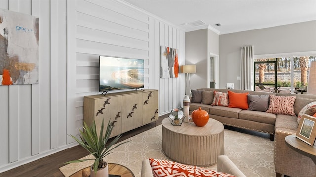 living area with crown molding, visible vents, and wood finished floors