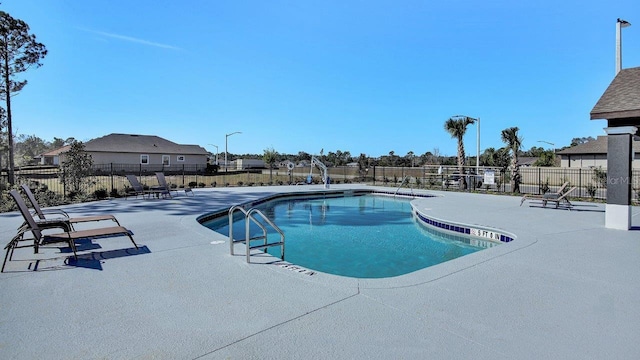 pool with a patio and fence