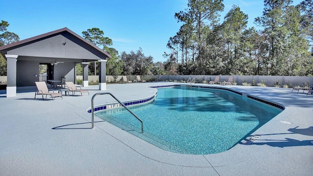 community pool with ceiling fan, a patio area, and fence