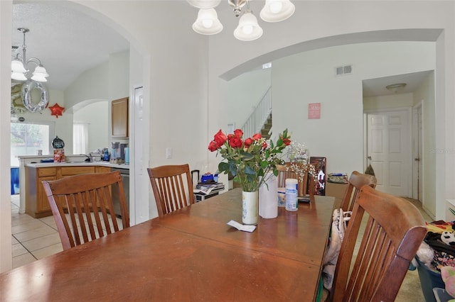 1305 Rebecca Dr, Haines City, FL 33844 - dining space featuring a chandelier, arched walkways, lofted ceiling, light tile patterned floors, and stairs