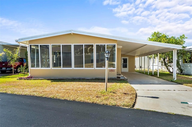151 Lookout Dr, Flagler Beach, FL 32136 - view of front of home with an attached carport, concrete driveway, a front yard, and a sunroom