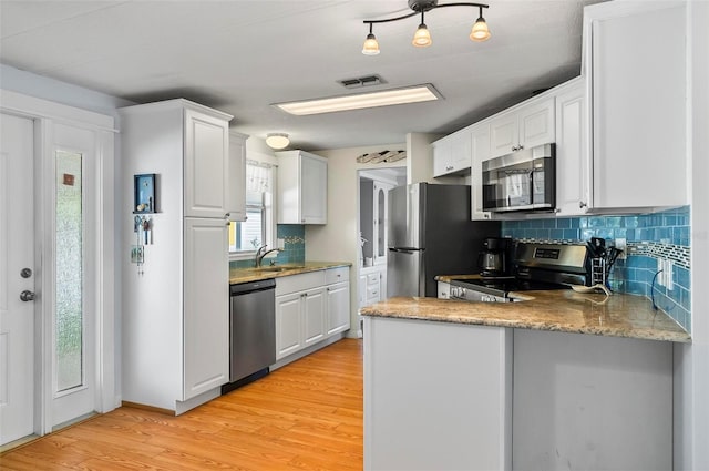 151 Lookout Dr, Flagler Beach, FL 32136 - kitchen with appliances with stainless steel finishes, backsplash, light wood-style floors, a peninsula, and white cabinetry