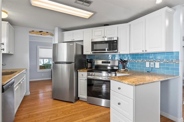 151 Lookout Dr, Flagler Beach, FL 32136 - kitchen with appliances with stainless steel finishes, white cabinets, and light wood-style flooring