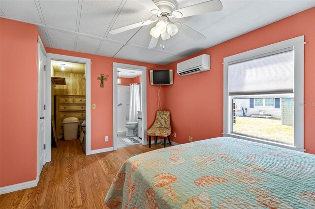 151 Lookout Dr, Flagler Beach, FL 32136 - bedroom with a wall unit AC, wood finished floors, ensuite bathroom, baseboards, and ceiling fan