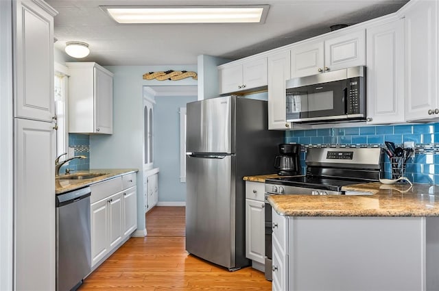 151 Lookout Dr, Flagler Beach, FL 32136 - kitchen with stainless steel appliances, a sink, decorative backsplash, white cabinets, and light wood-type flooring