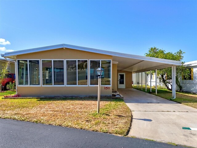 151 Lookout Dr, Flagler Beach, FL 32136 - view of front of property with a carport, concrete driveway, and a front lawn