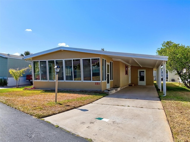151 Lookout Dr, Flagler Beach, FL 32136 - manufactured / mobile home with a front lawn, a carport, driveway, and a sunroom