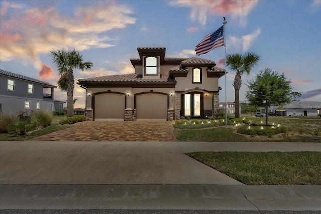 3 Menorca Way, Palm Coast, FL 32137 - mediterranean / spanish house featuring stucco siding, driveway, stone siding, a tile roof, and a garage