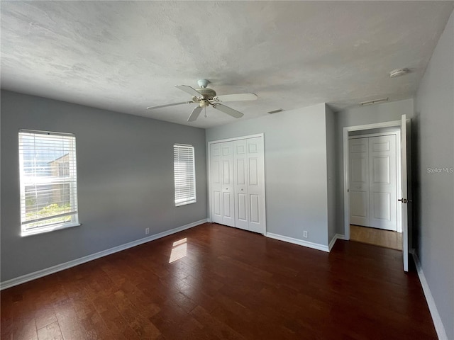 unfurnished bedroom featuring baseboards, wood finished floors, a closet, and a ceiling fan