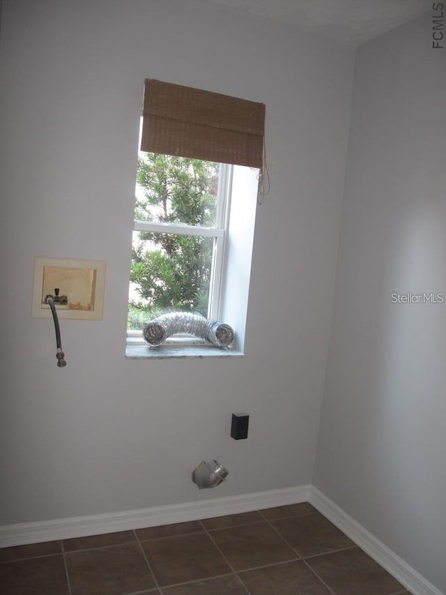 clothes washing area featuring dark tile patterned flooring, baseboards, and washer hookup