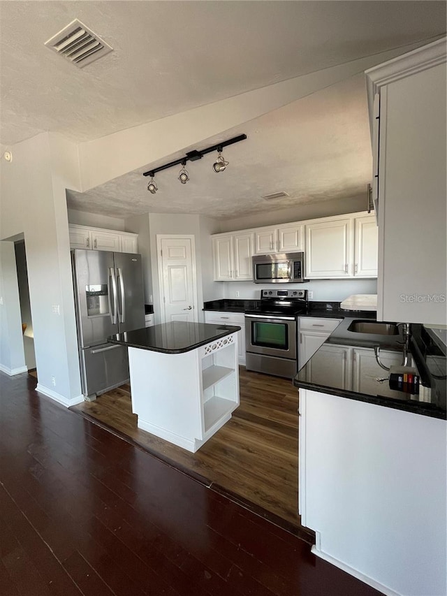 kitchen featuring appliances with stainless steel finishes, dark countertops, white cabinetry, open shelves, and dark wood-style flooring