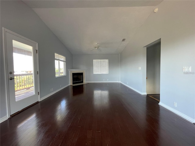 unfurnished living room featuring lofted ceiling, dark wood-style flooring, a ceiling fan, a fireplace with flush hearth, and baseboards