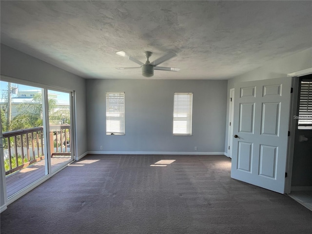 spare room with a ceiling fan, dark carpet, plenty of natural light, baseboards, and a textured ceiling